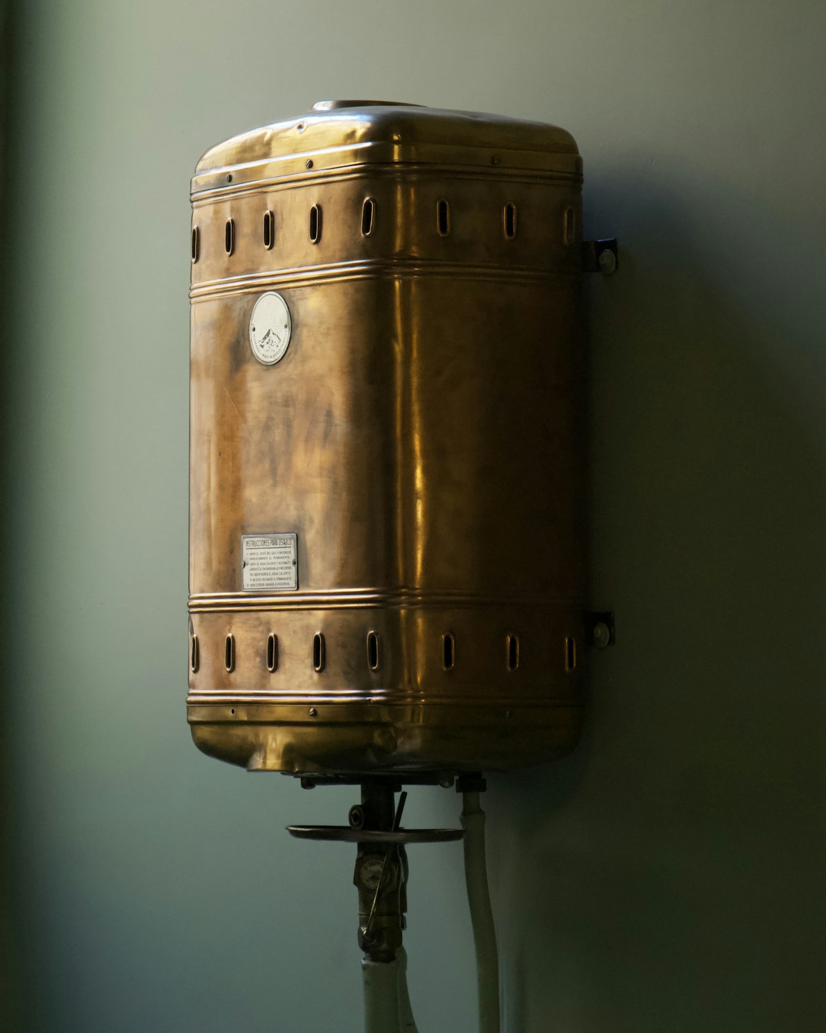 Decades-old copper geyser mounted on the wall before replacement